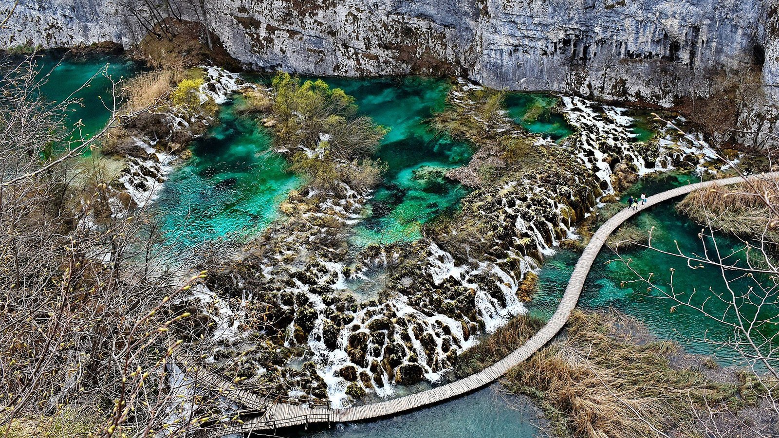 Wooden boardwalk between turquoise lakes and waterfalls in Plitvice Lakes National Park